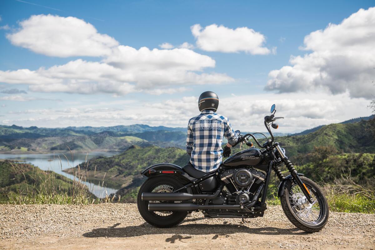 Homem sentado em uma moto, observando uma paisagem.