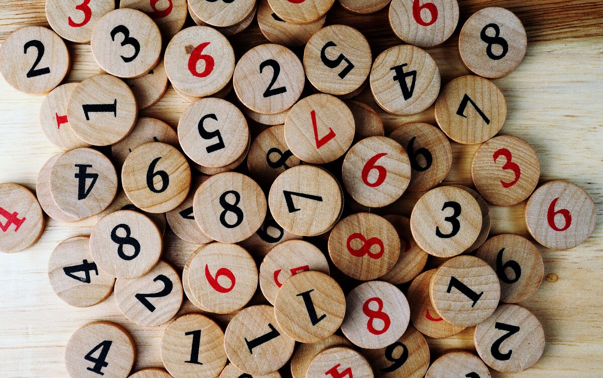 Pedaços de madeira com números gravados espalhados sobre mesa.