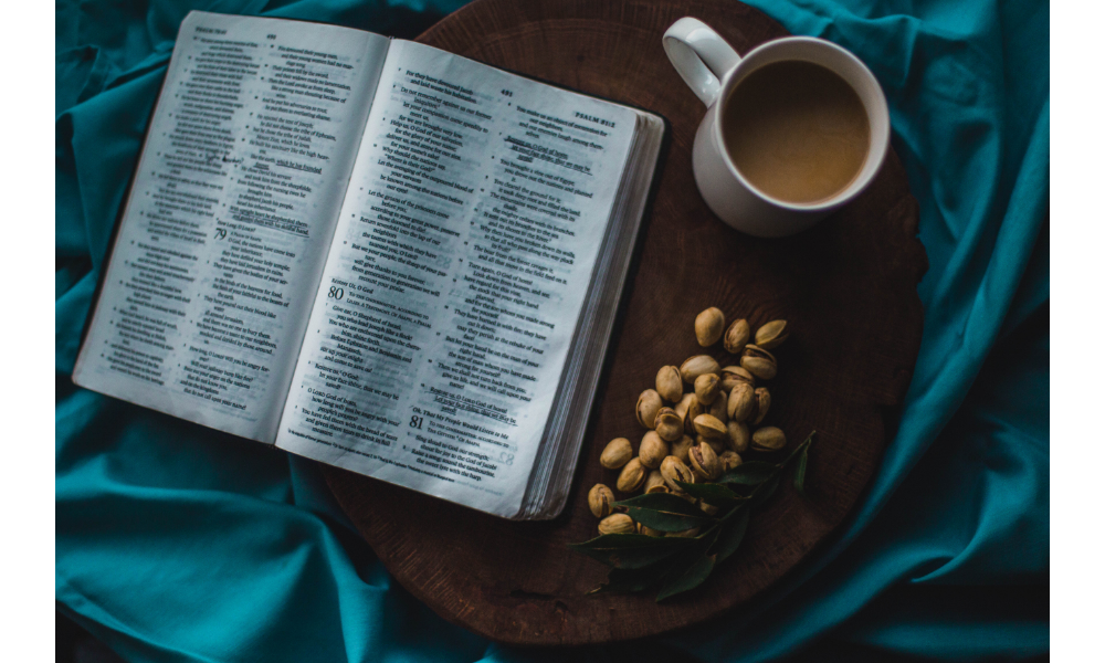 Foto de uma bíblia aberta com uma xícara de café ao lado.