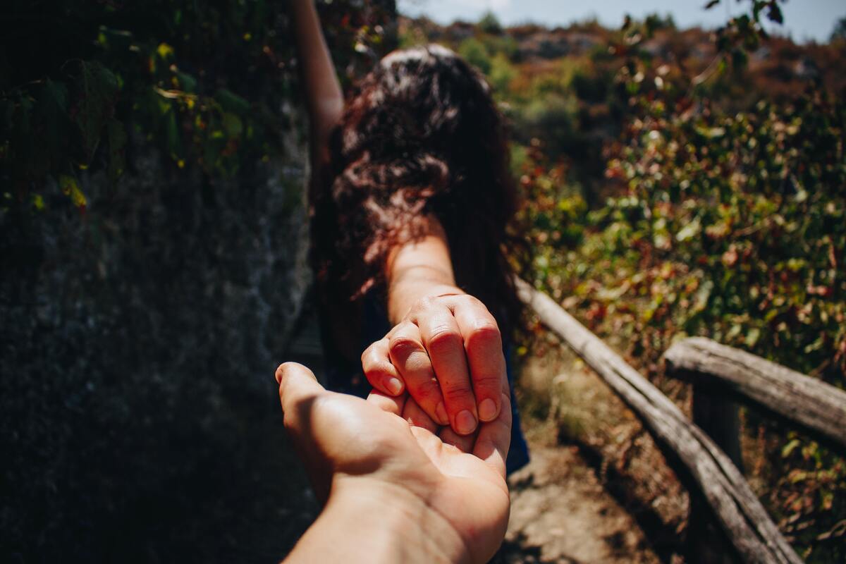 Mão de um homem segurando a mão de uma mulher.