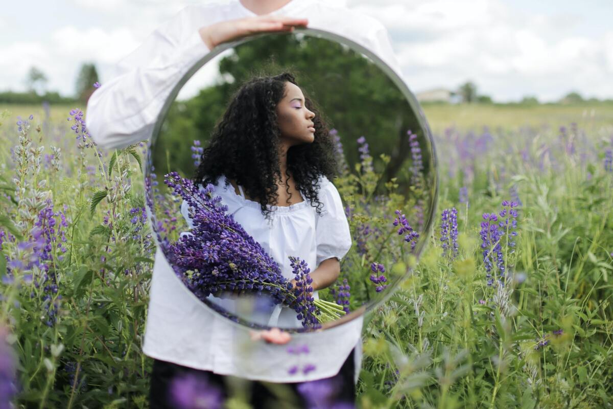 Mulher em campo de flores refletida em espelho
