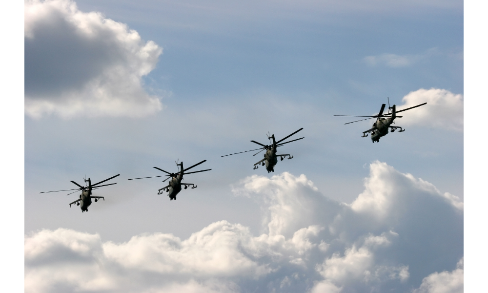 Quatro helicópteros em voo no céu.