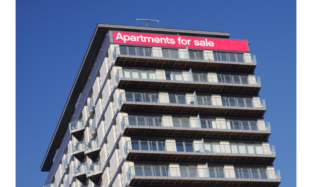 Prédio alto com placa em cima indicando "apartments for sale" (apartamento à venda).