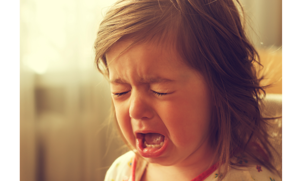 Menina criança chorando muito com a boca aberta.