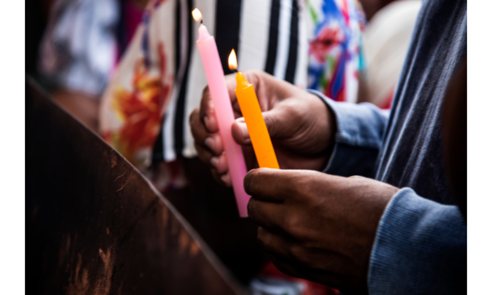Mãos segurando velas coloridas para um ritual religioso.