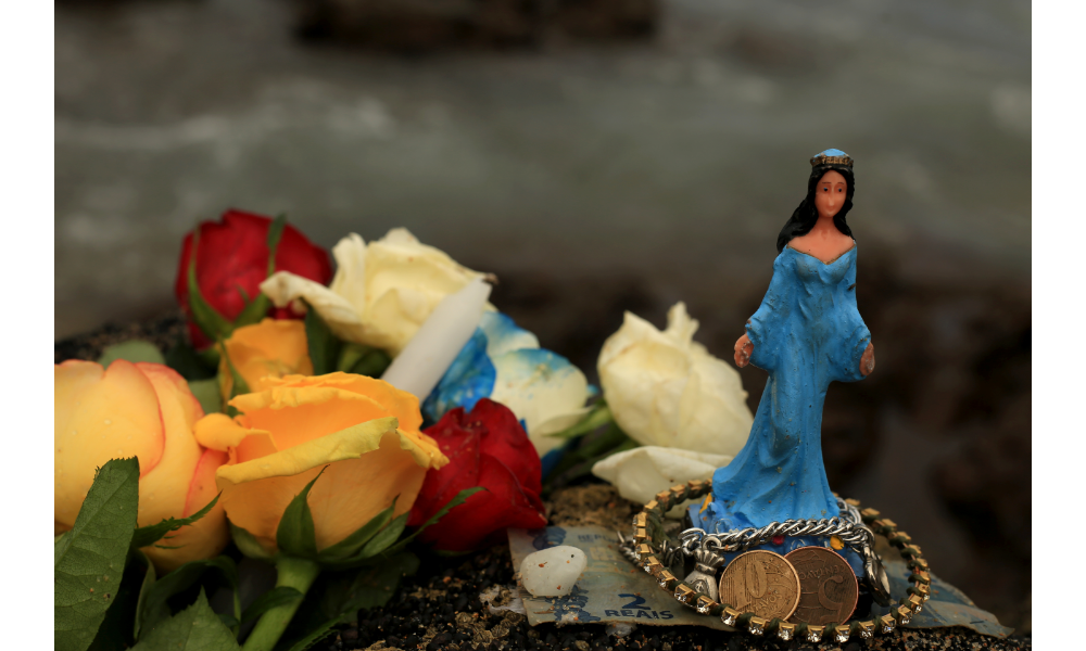 Imagem de Iemanjá ao lado de flores e moedas.