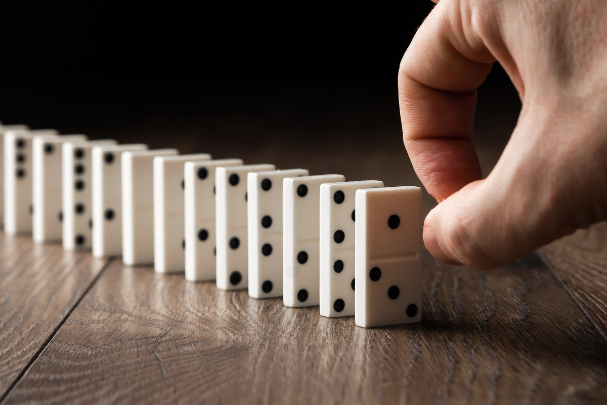 homem aponta dedo pra fila de dominós