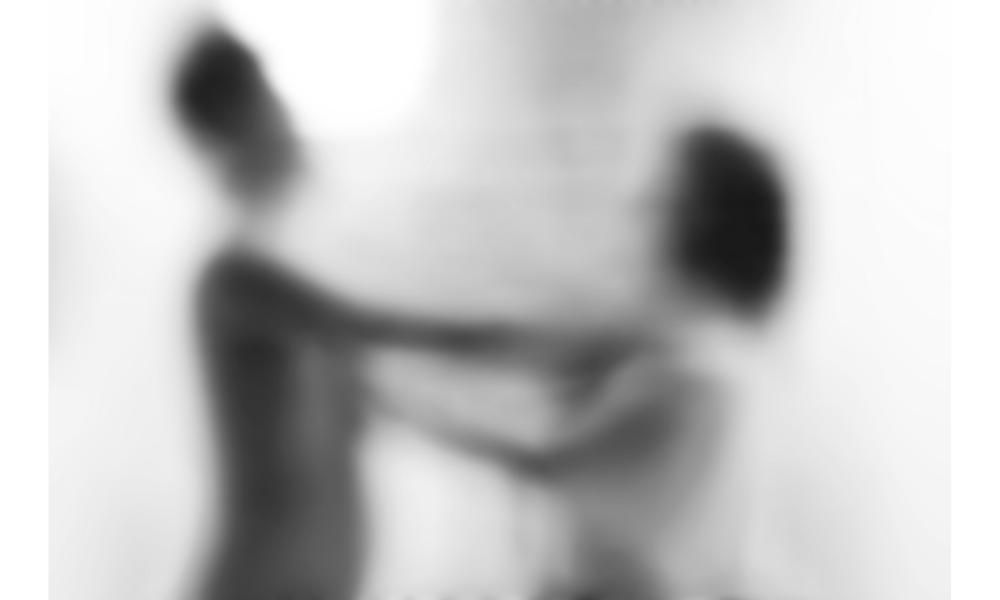 Imagem desfocada preta e branca mostrando duas pessoas brigando.