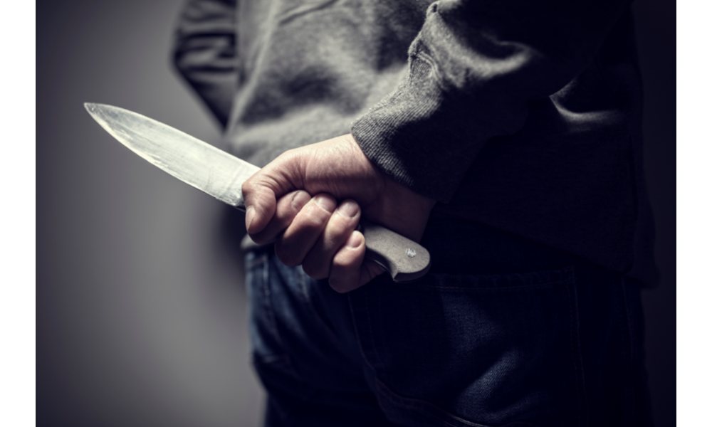 Pessoa de costas com uma faca na mão.
