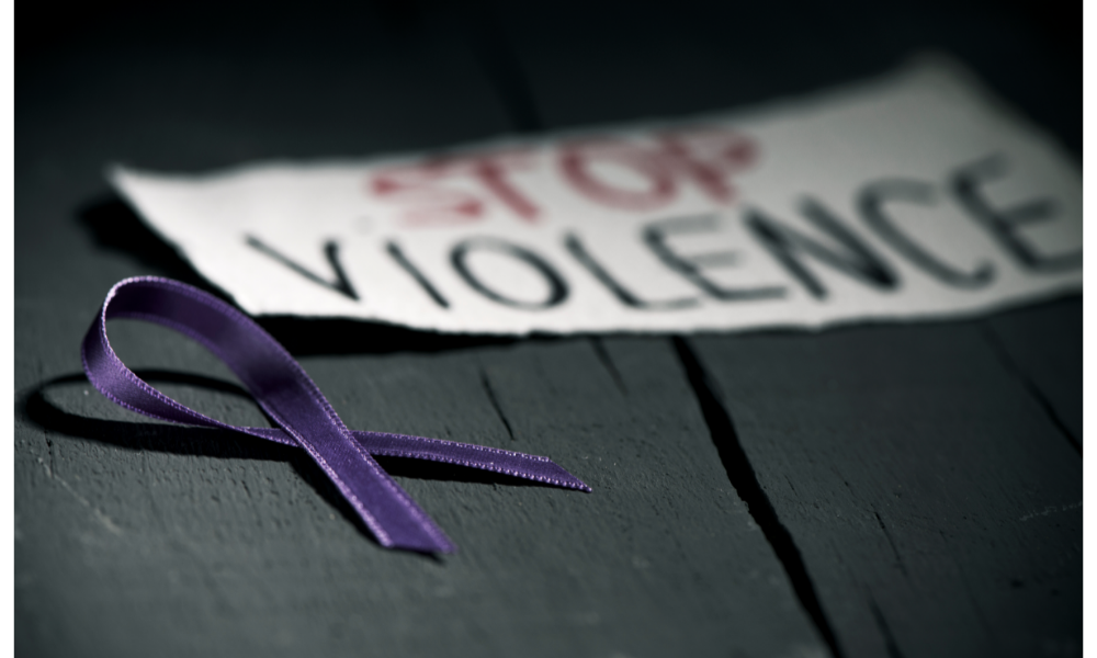 Fita roxa, símbolo de prevenção da violência contra a mulher ao lado de um papale escrito "Stop violence" 