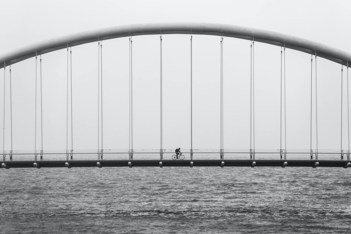 Homem andando de bicicleta em uma ponte.