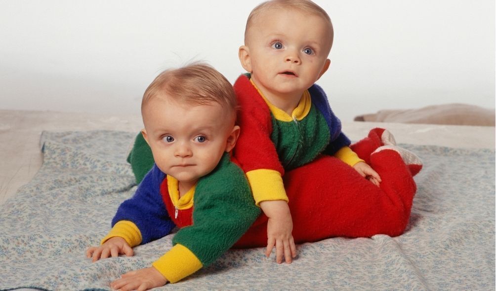 Dois bebês gêmeos com roupas coloridas