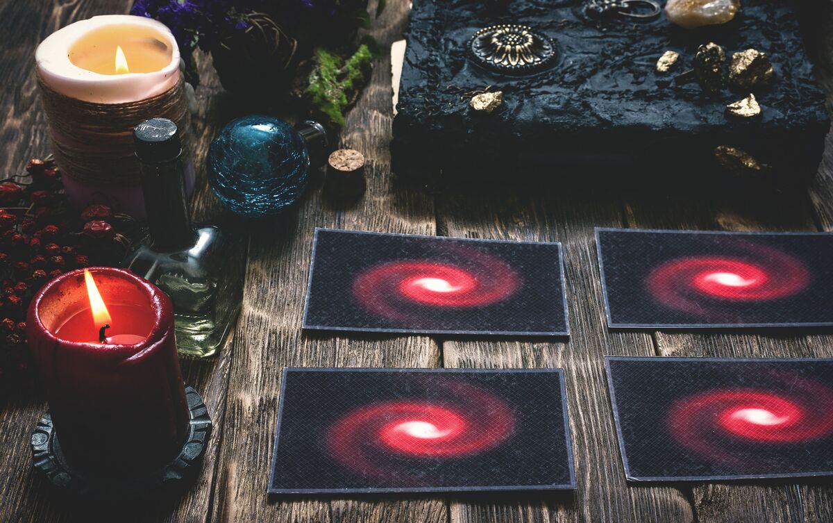 Cartas de Tarot enfileiradas sobre mesa com velas ao redor.