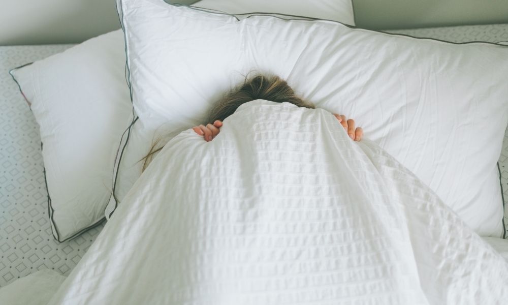 pessoa na cama escondida no lençol