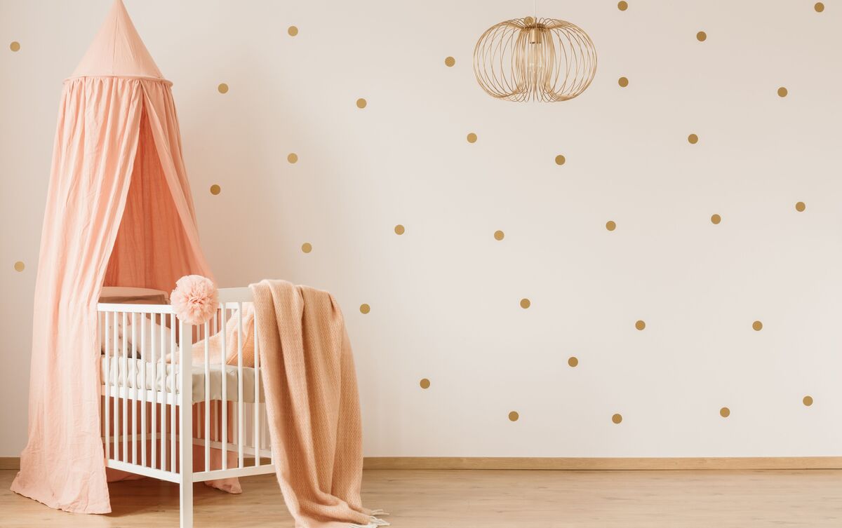 Berço branco com lençóis cor-de-rosa em quarto de bebê.