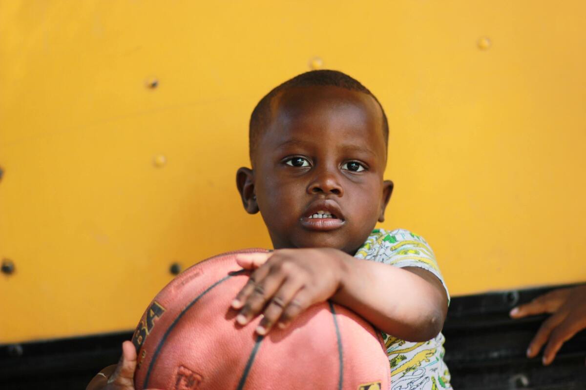Menino negro segurando uma bola de basquete.