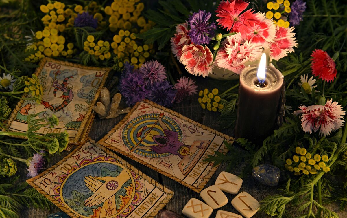 Cartas de Tarot combinadas em meio a mesa com plantas e flores.
