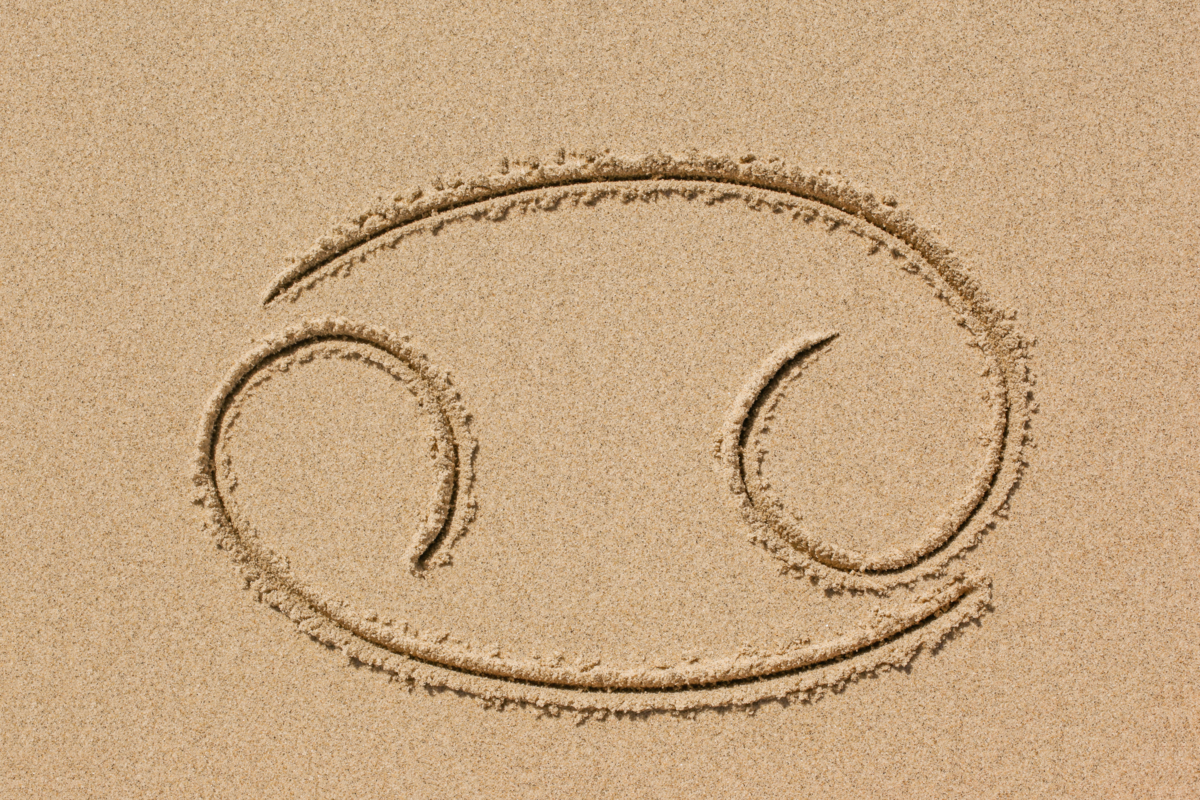 Símbolo do signo de Câncer desenhado na areia.