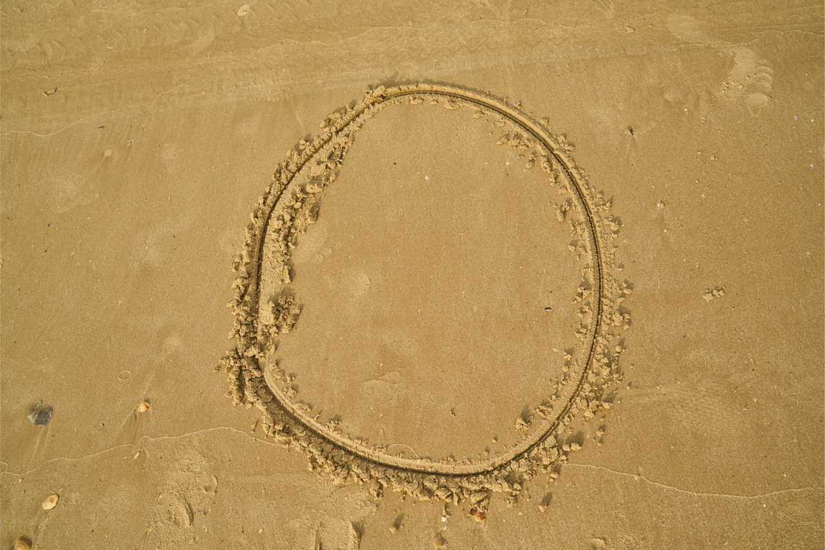 Número 0 desenhado na areia da praia. 