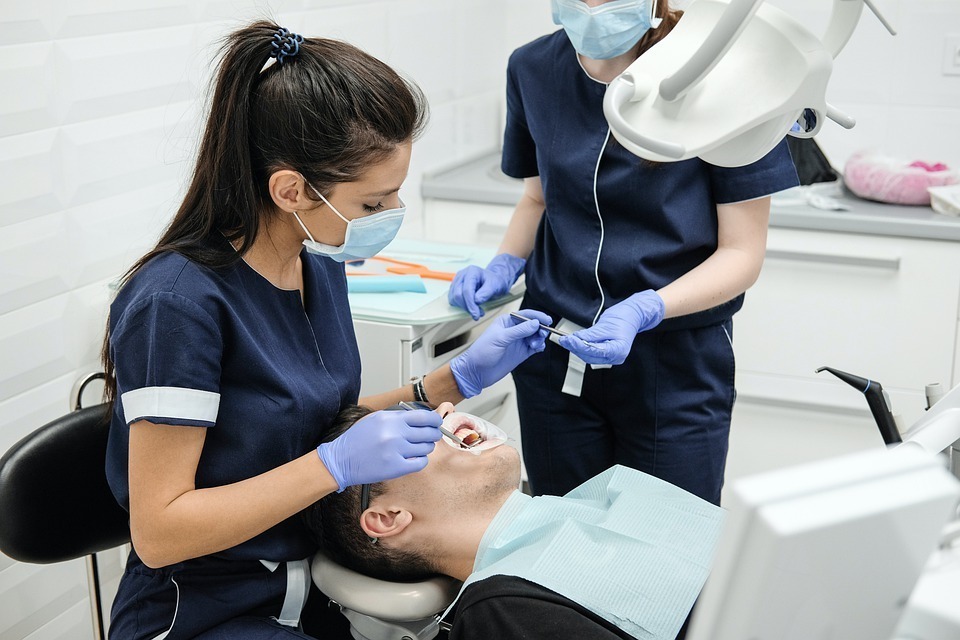 Duas dentistas atendendo um paciente.