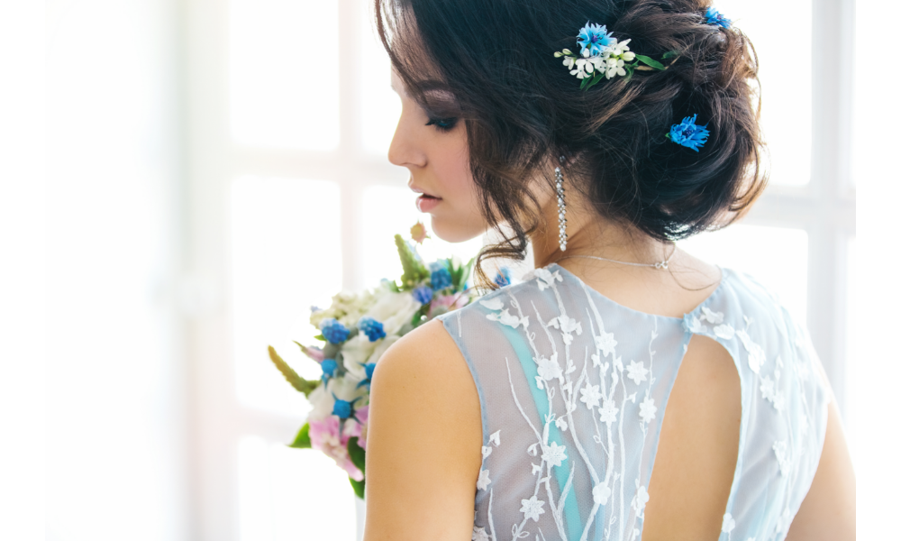 Mulher de costas com vestido de noiva e buquê azuis.