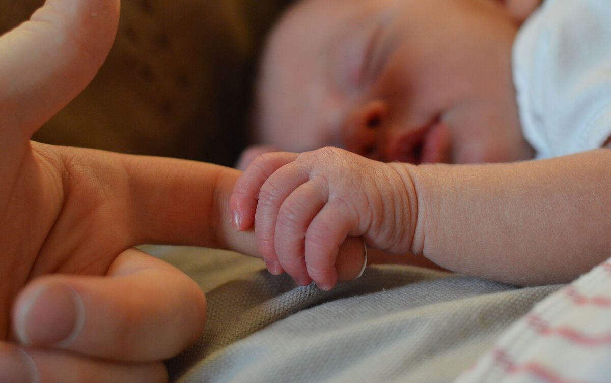 Bebê segurando dedo dos pais.