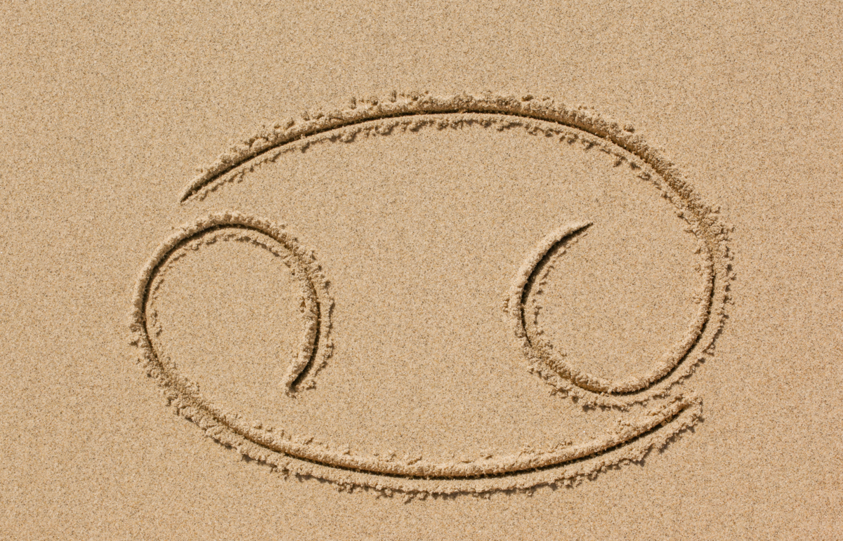 Símbolo do signo de Câncer desenhado na areia.