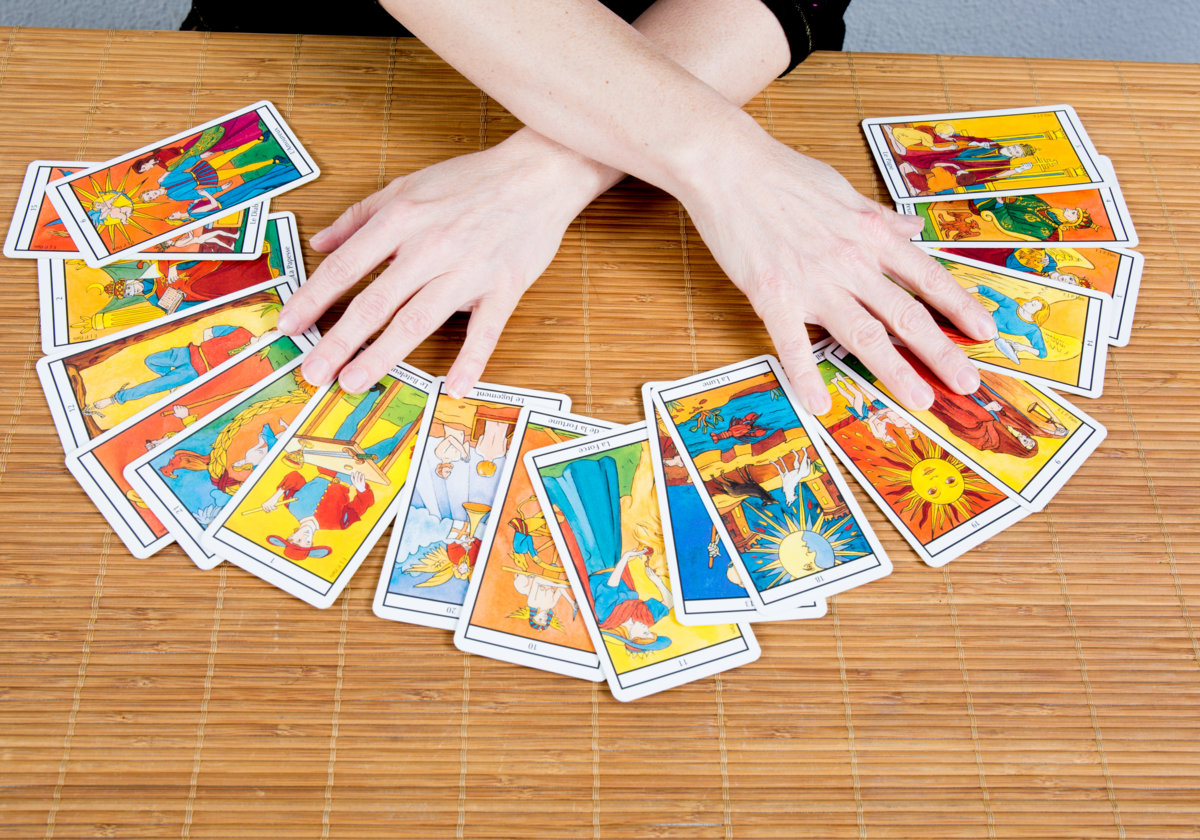 Mãos femininas mexendo em cartas de Tarot.