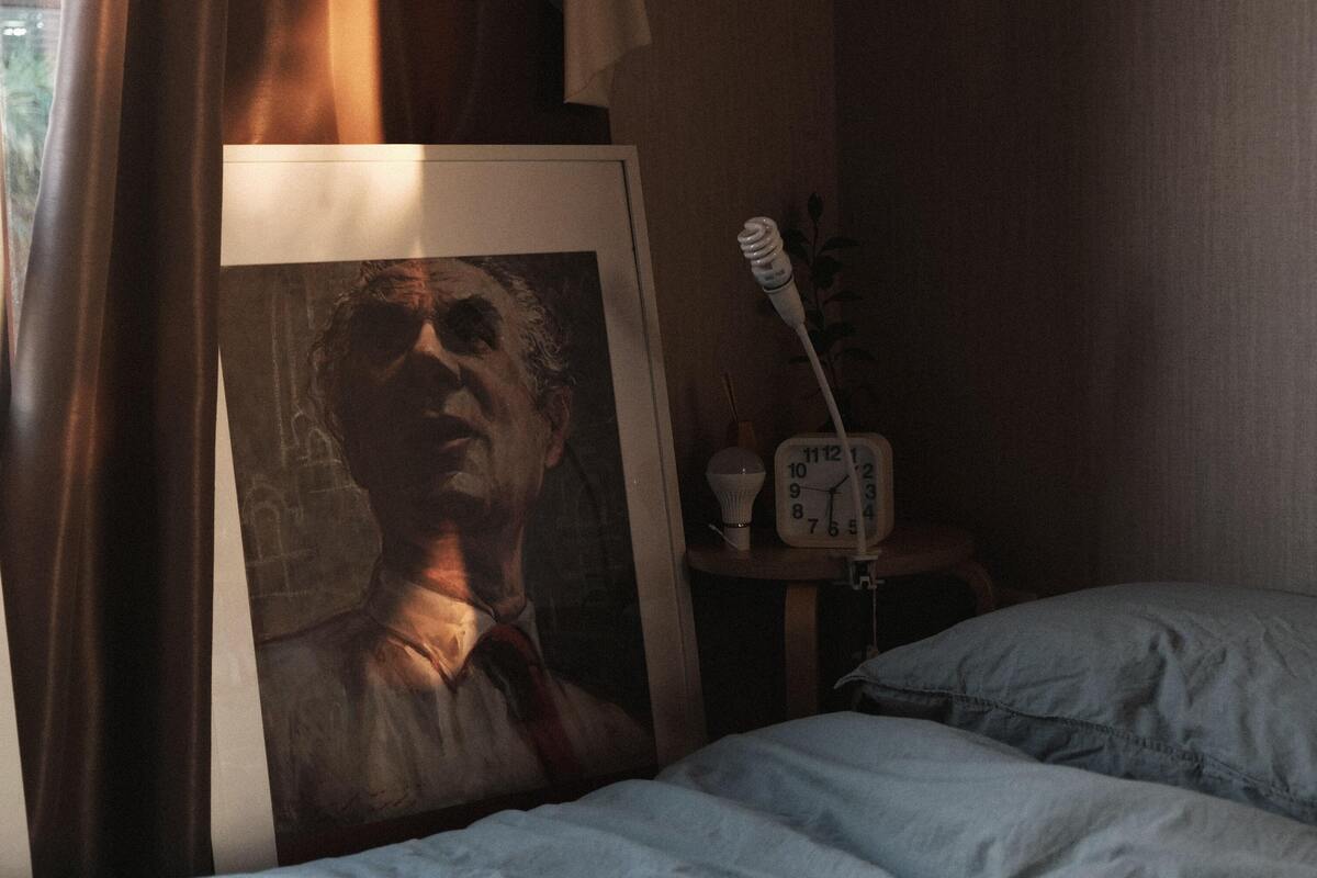 Retrato de um homem atrás da cama.