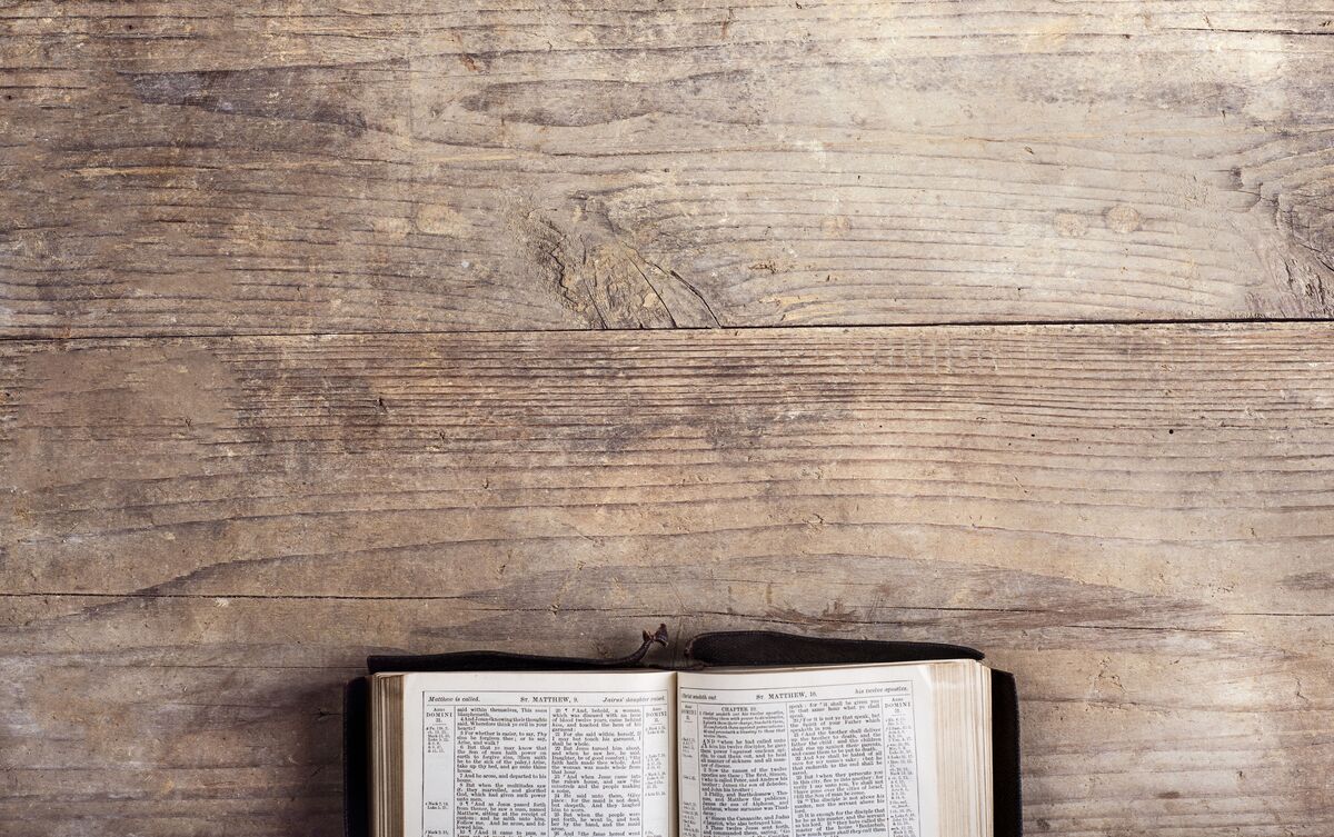 Bíblia aberta sobre mesa de madeira.