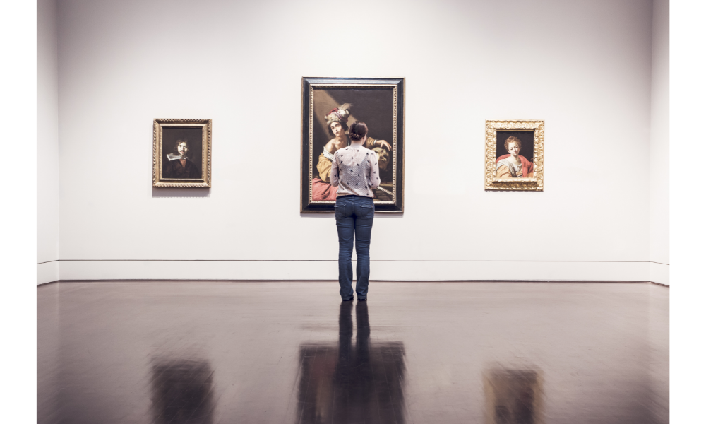 Mulher em um museu olhando um quadro.