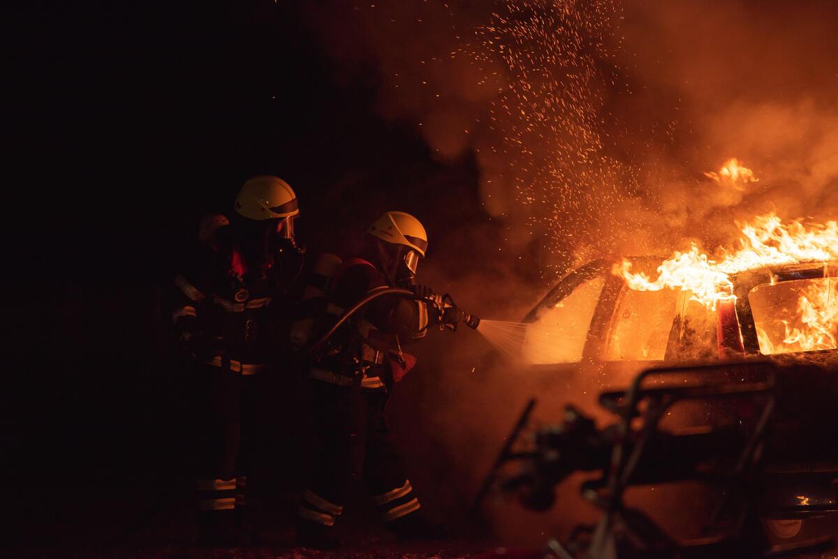 Bombeiros apagando fogo de um carro.