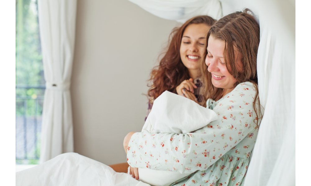 Irmãs juntas em uma cama, uma delas com um bebê nos braços.