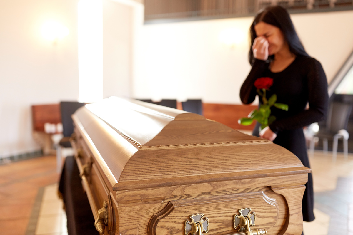 Mãe chorando próximo a caixão de filho morto.