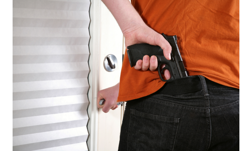 Homem segurando uma arma entrando por uma porta.
