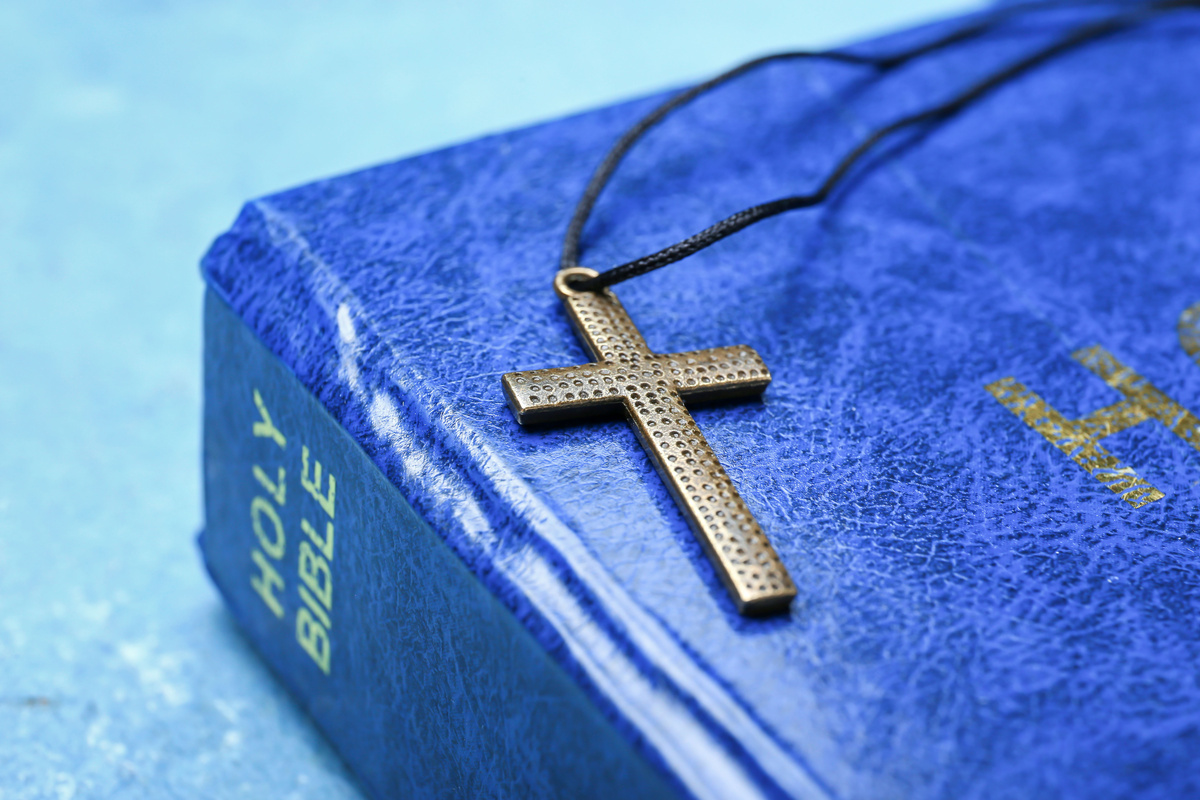 Bíblia azul com um crucifixo em cima.