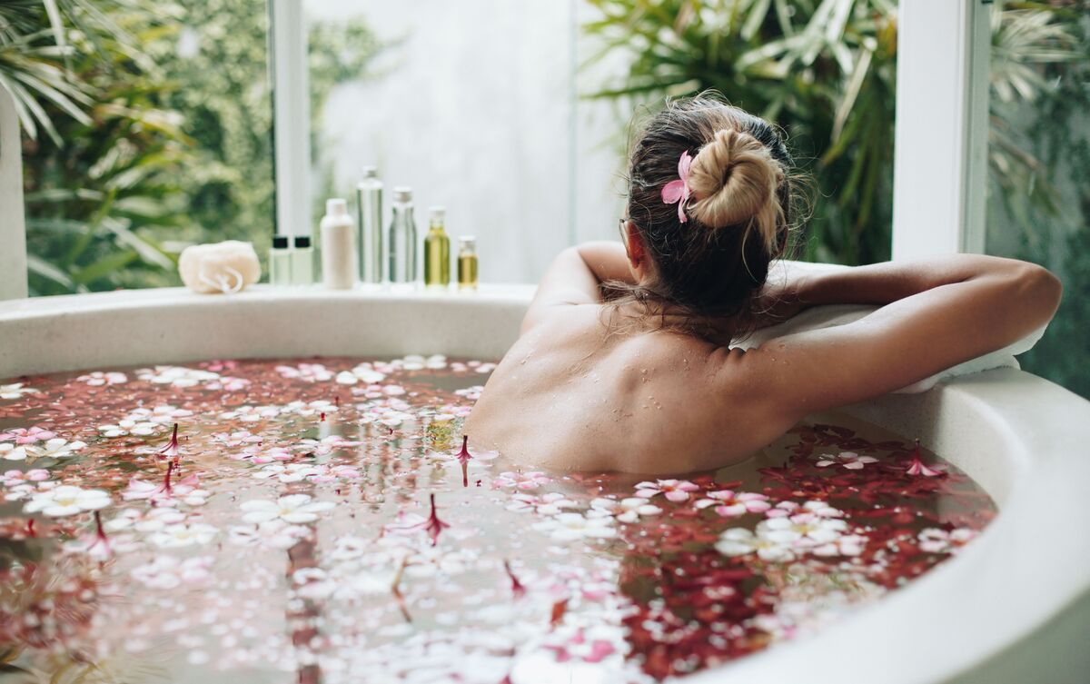 Mulher deitada em banheira com rosas.
