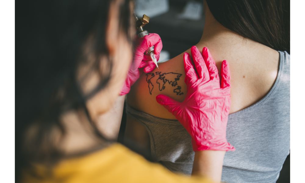 Pessoa tatuando as costas de alguém com um mapa do mundo.