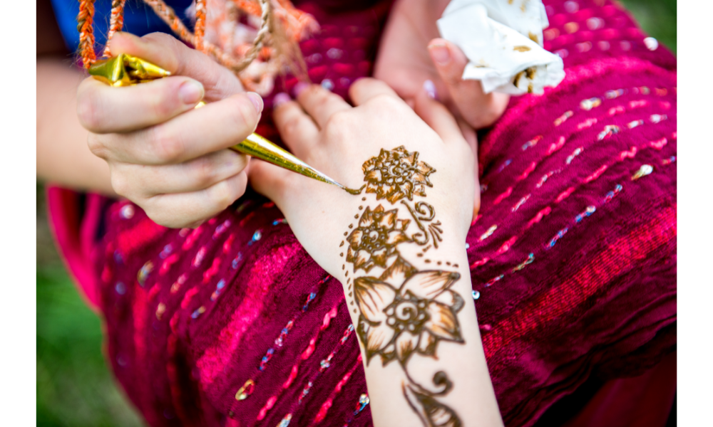 Pessoa fazendo uma tatuagem de henna na mão de uma mulher.