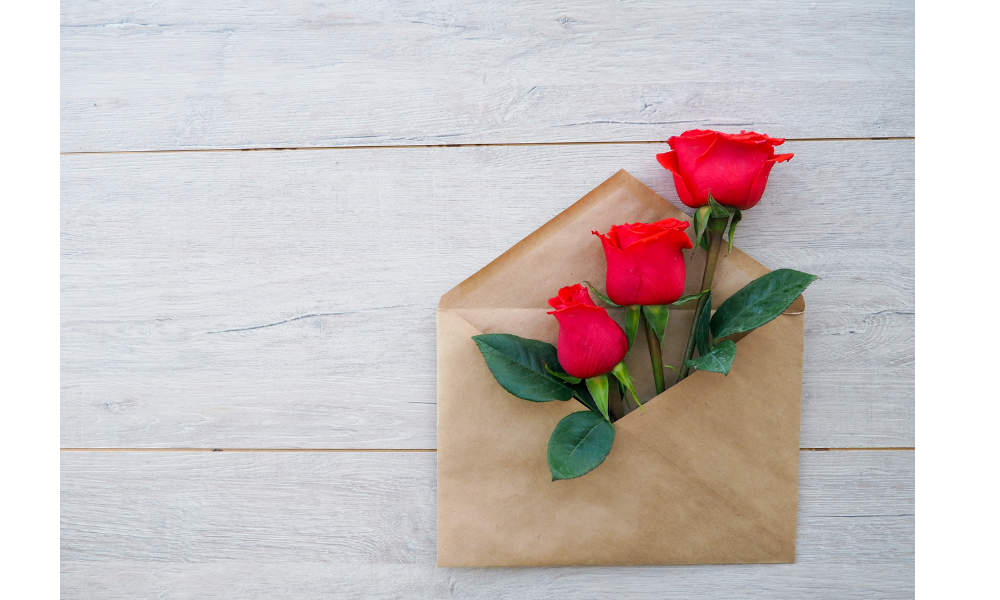 Envelope com três rosas vermelhas dentro.