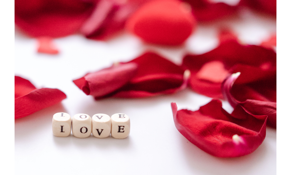 Pétalas de rosas e pequenos dados formando a palavra "love" - amor.