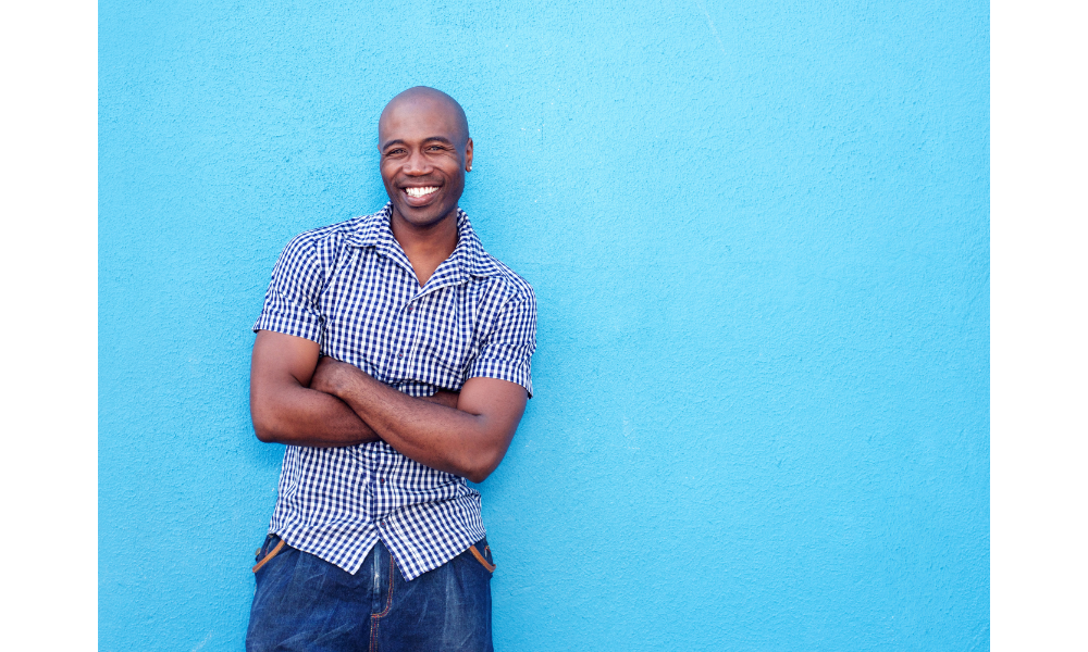 Homem negro sorrindo em um fundo azul.