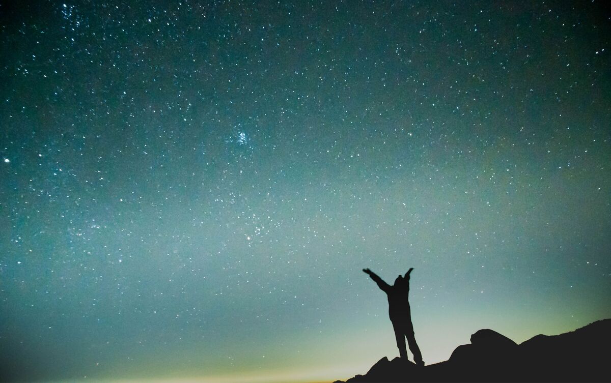Homem observando céu com estrelas.
