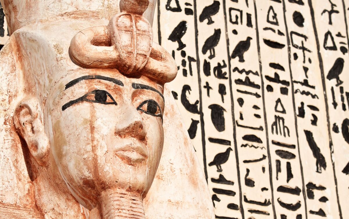 Estátua de deusa egípcia e hieróglifos.