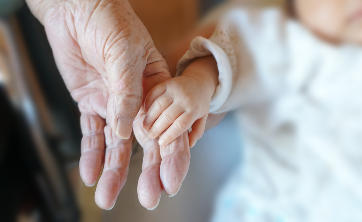 bebê segurando mão de idoso