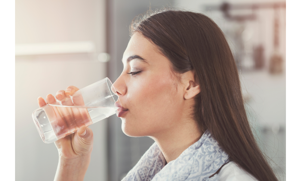 Mulher bebendo água em um copo.