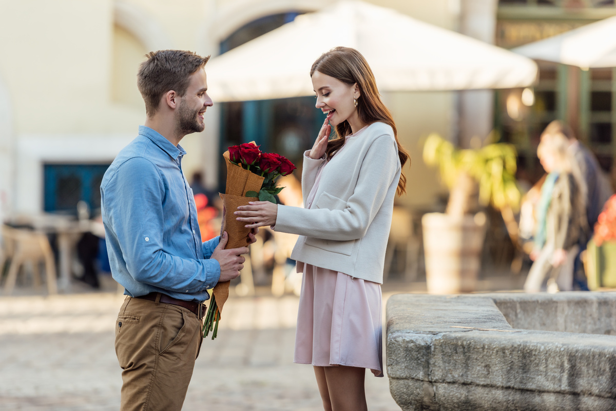 um homem entregando um buquê de flores para uma mulher