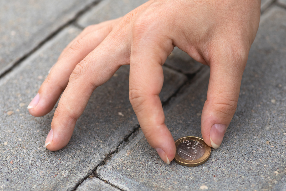 Pessoa achando moeda no chão