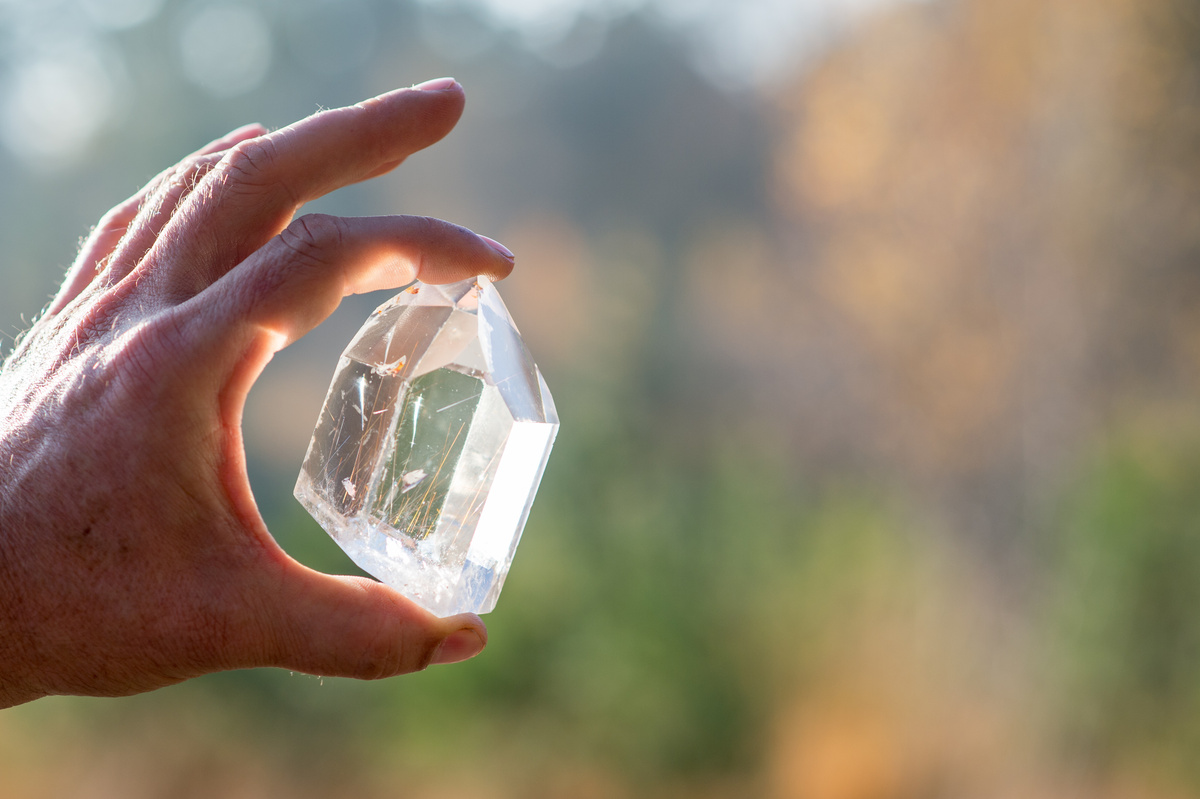 Mão segurando cristal transparente para cima.