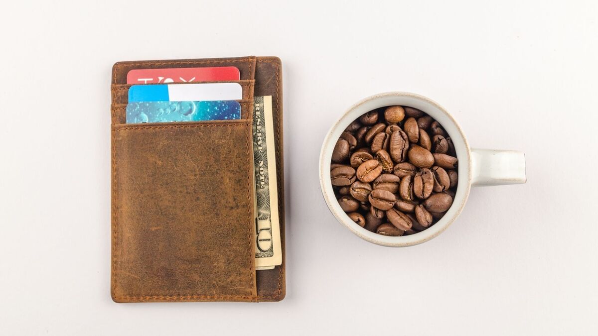 Uma carteira ao lado de um copo de café.
